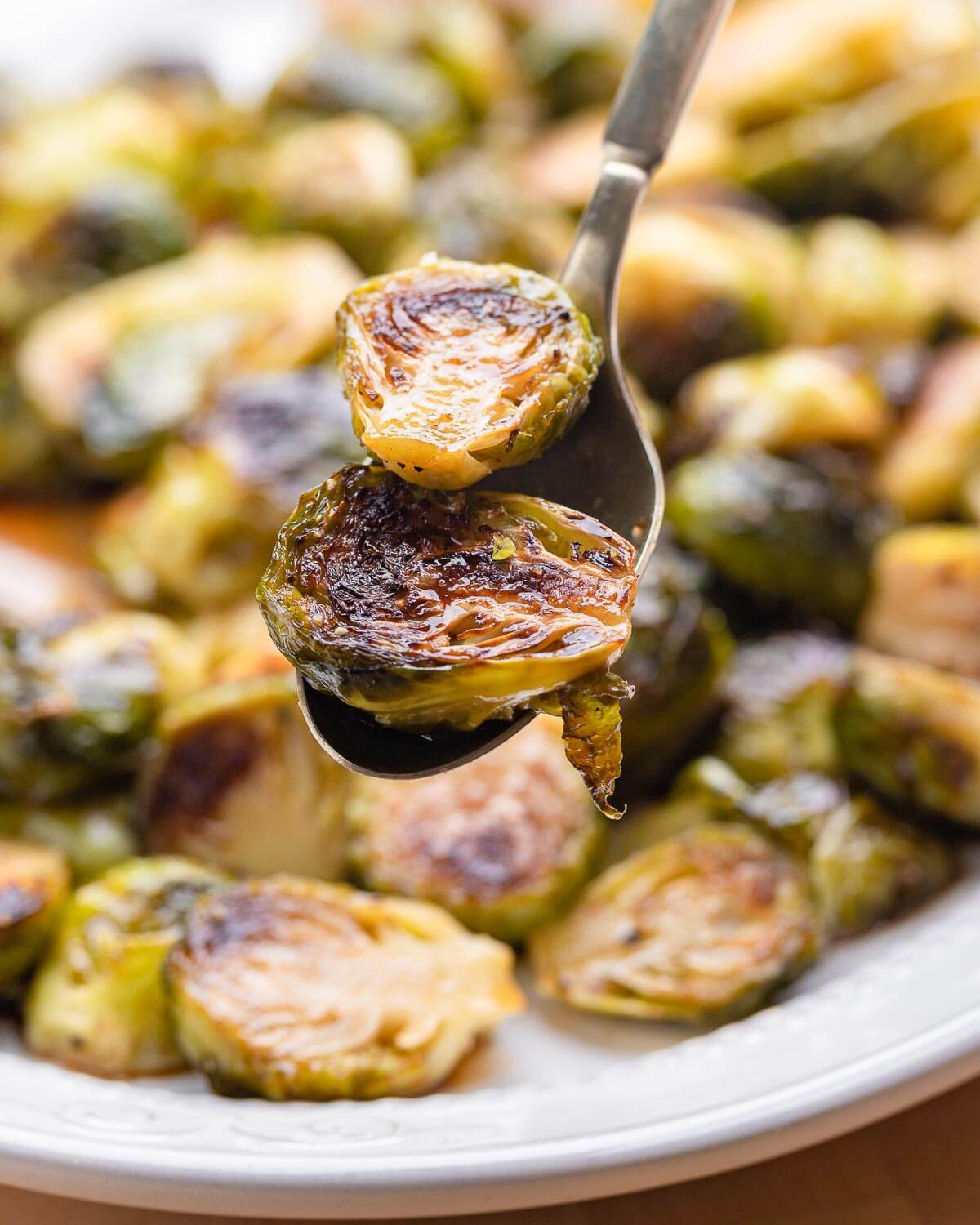 Spoon holding 2 pieces of roasted brussels sprouts.