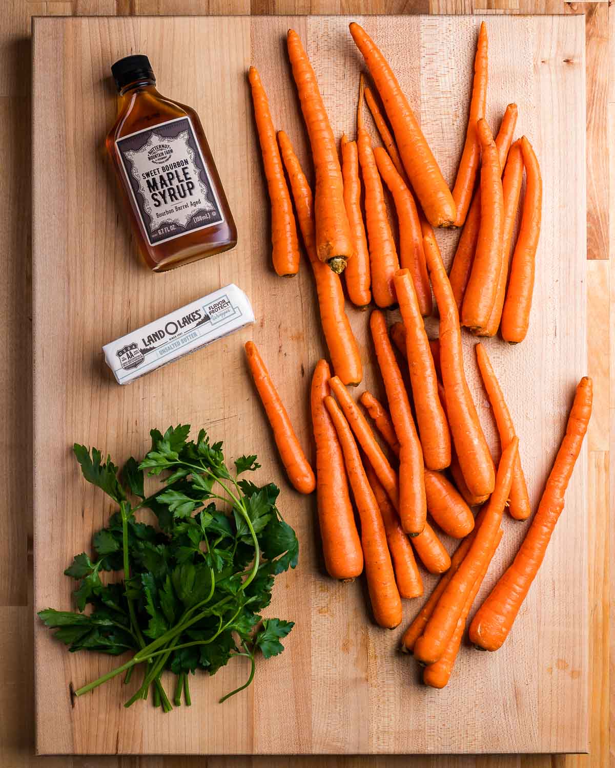 Ingredients shown: maple syrup, 1 stick of butter, parsley, and loose carrots.