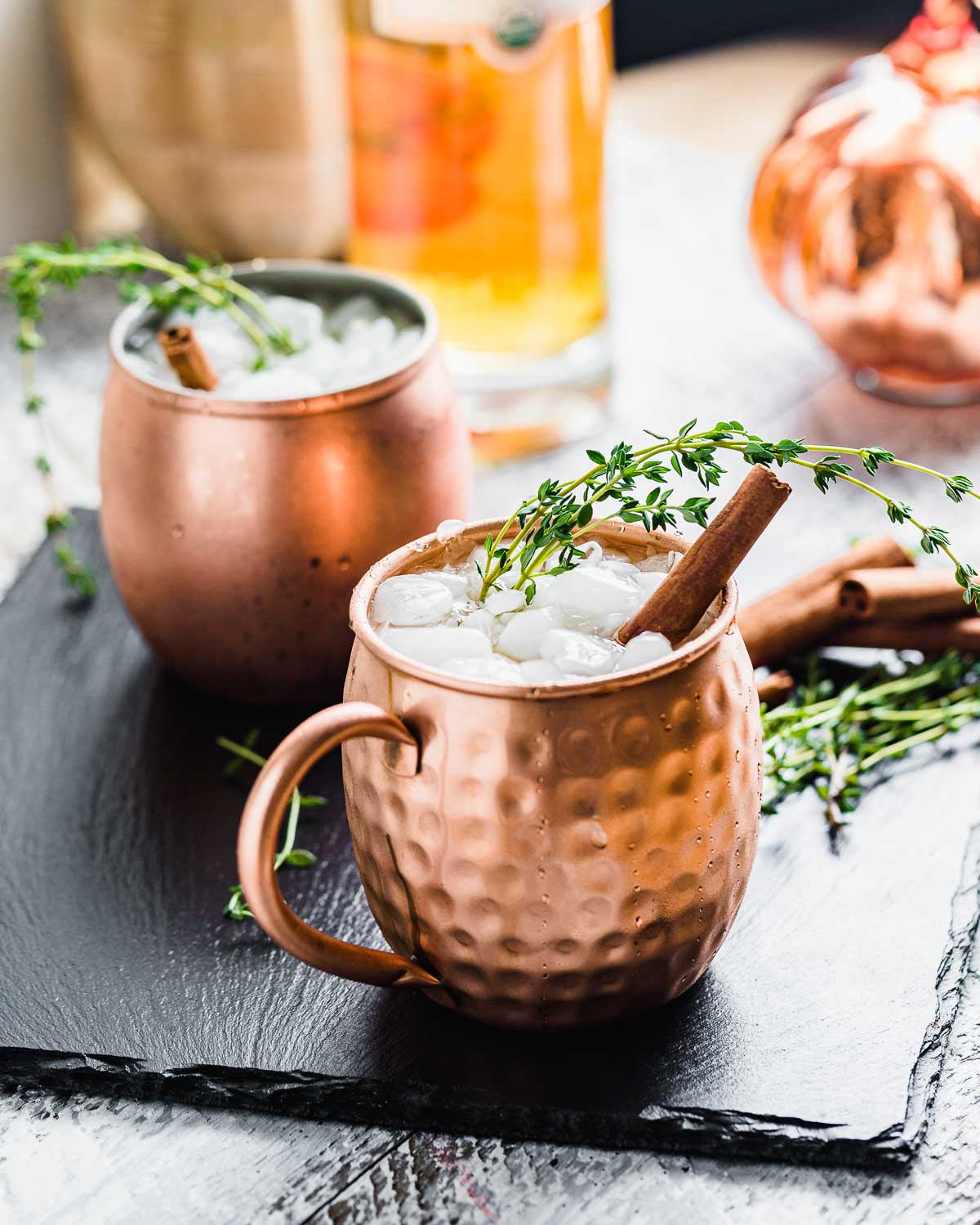 Two pumpkin spiced mules on black slate tile.