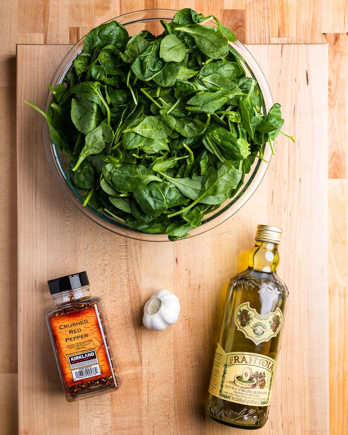 Ingredients shown: bowl of spinach, olive oil, garlic, and hot red pepper flakes.