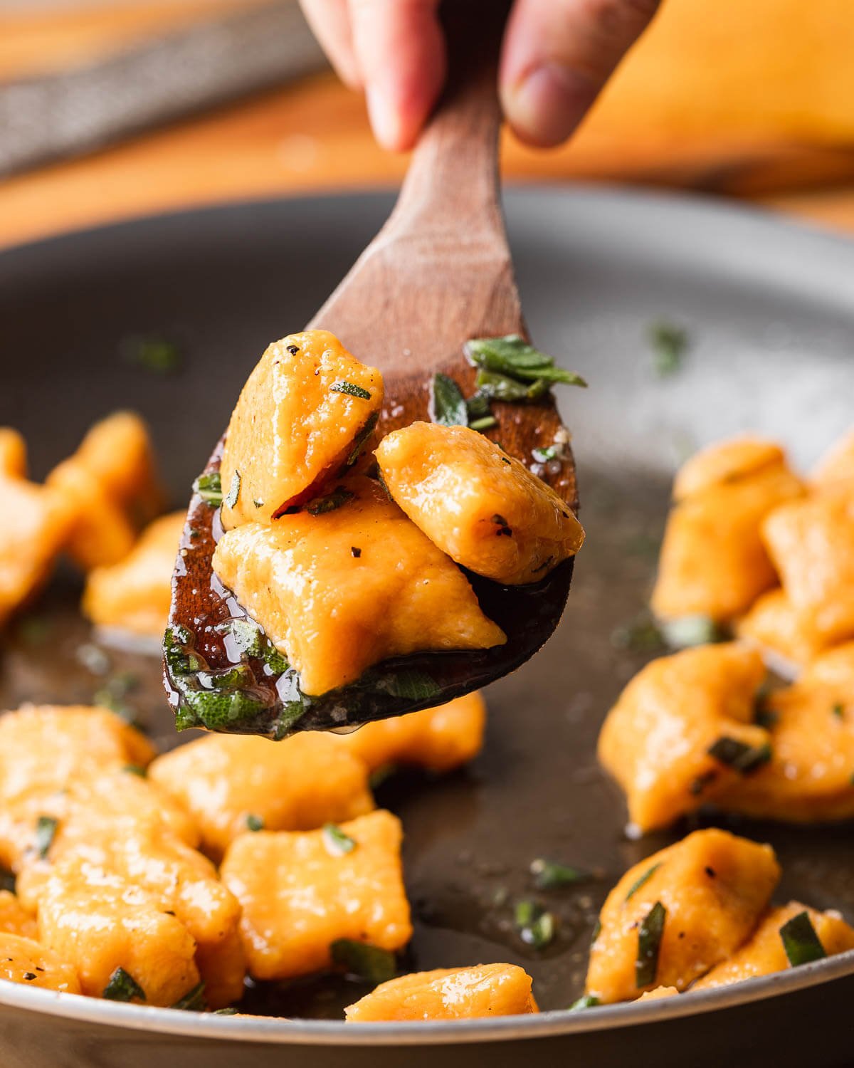 Wooden spoon holding 3 cooked sweet potato gnocchi.