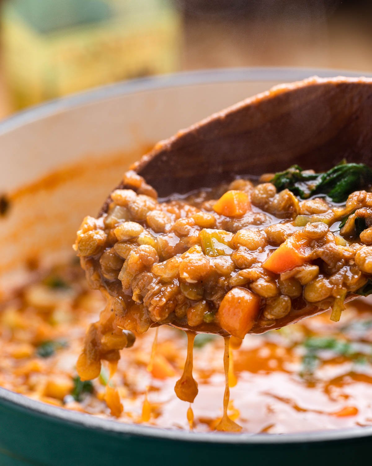 Large wooden ladle holding Italian lentil soup.