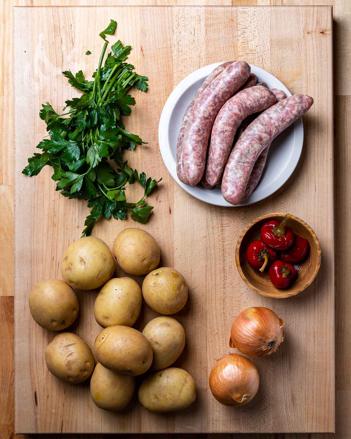 Ingredients shown: parsley, Italian sausage links, potatoes, onions, and cherry peppers.