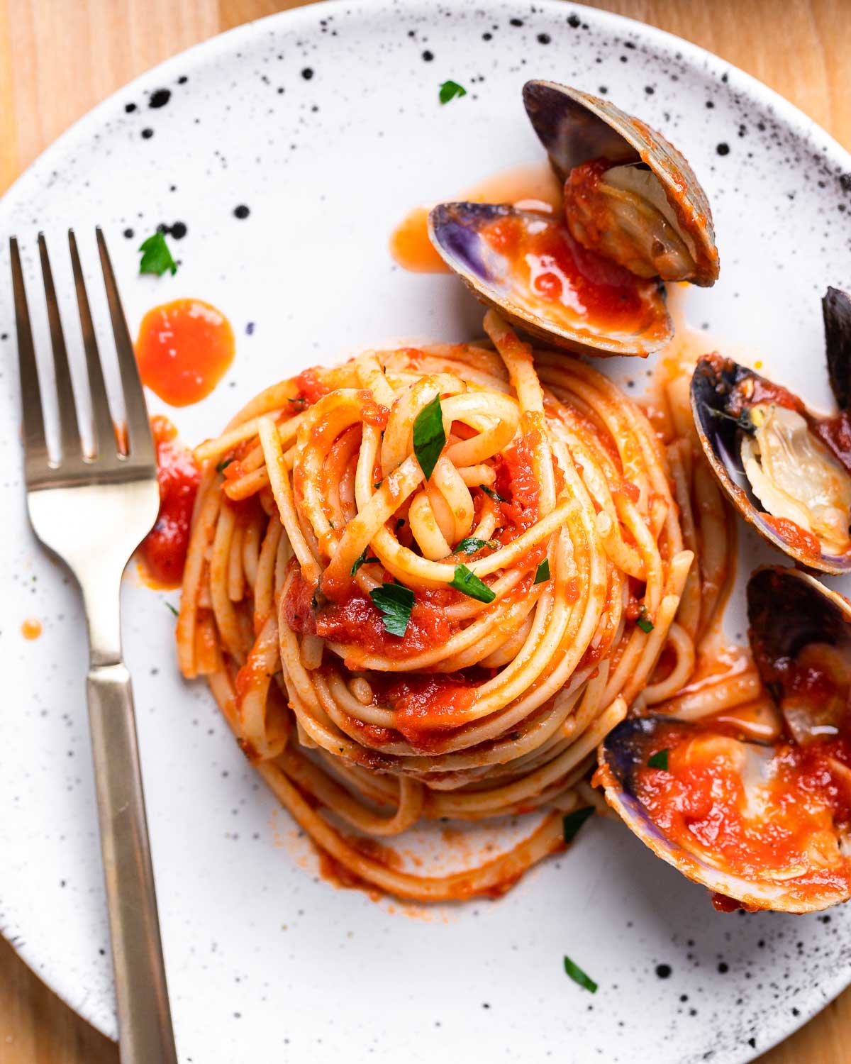 Small white plate of linguine with red clams sauce.