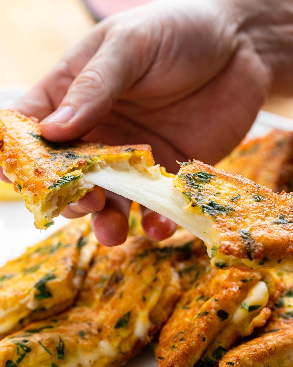 Hands pulling apart fried mozzarella sandwich.