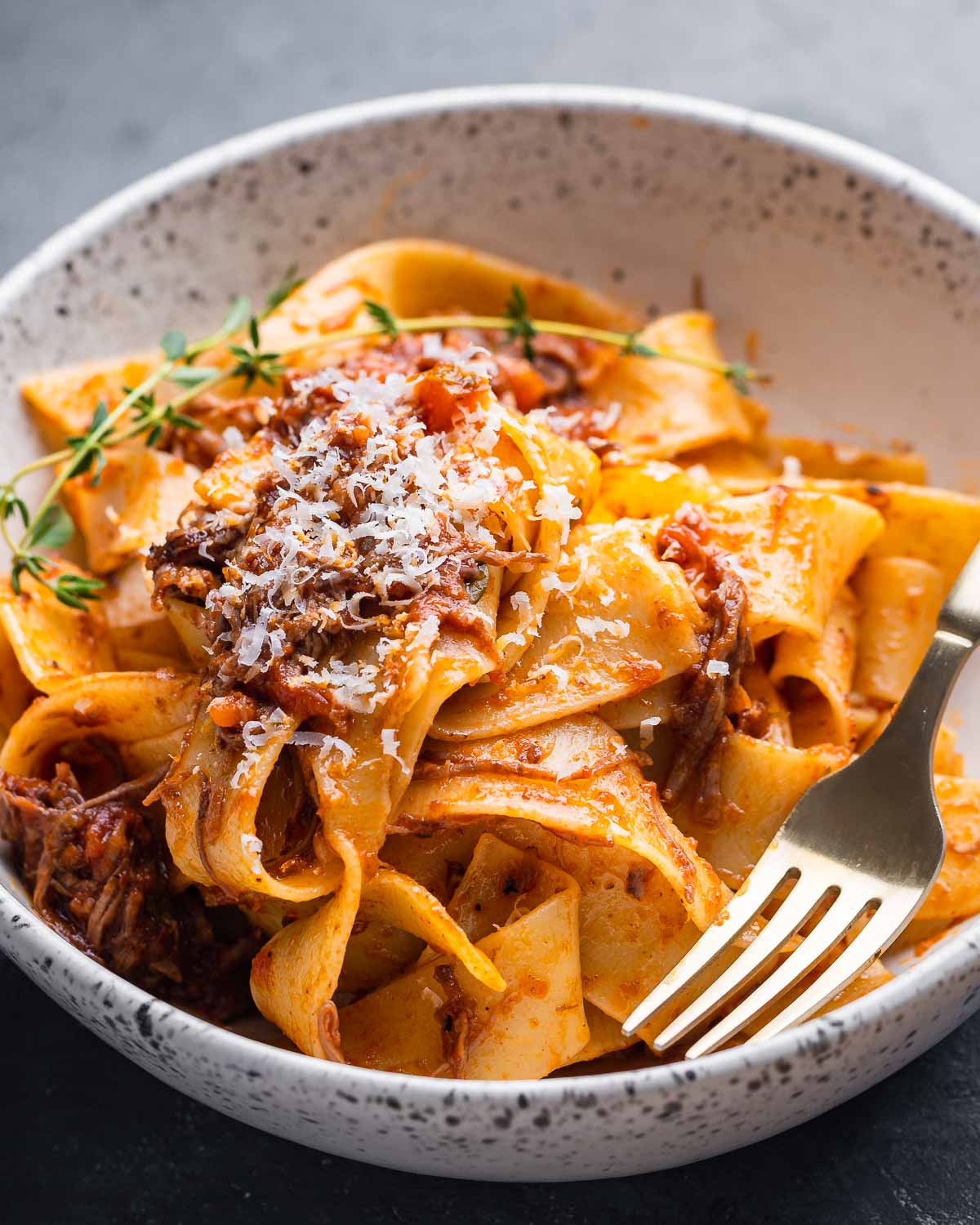 White bowl with short rib ragu over pappardelle.