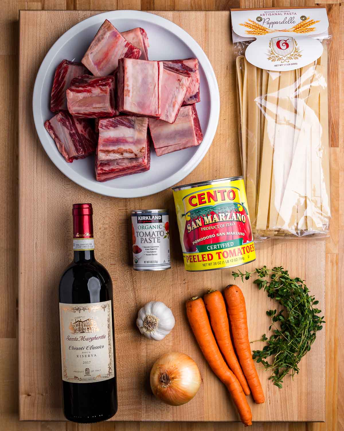 Ingredients shown: short ribs, pappardelle, canned tomatoes, red wine, garlic, onion, carrots, and thyme.