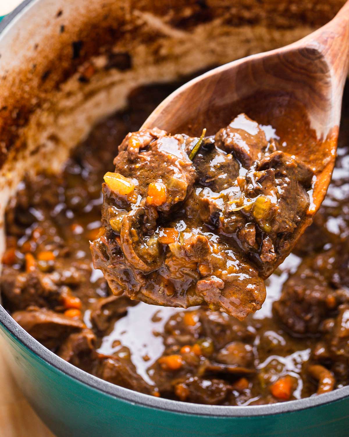 Large wooden spoon holding Italian beef stew.