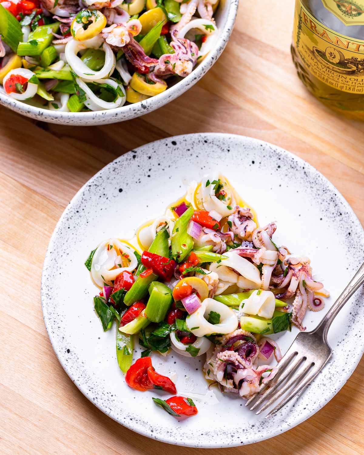 White plate with Italian calamari salad and fork.