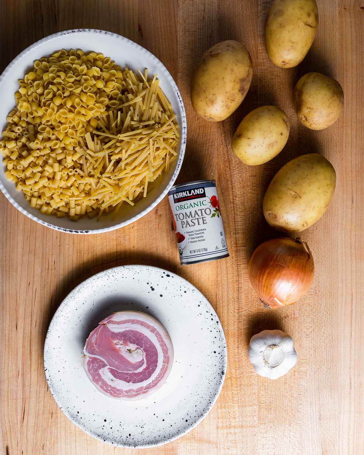 Ingredients shown: mixed pasta in bowl, potatoes, tomato pasta, pancetta, onion, and garlic.