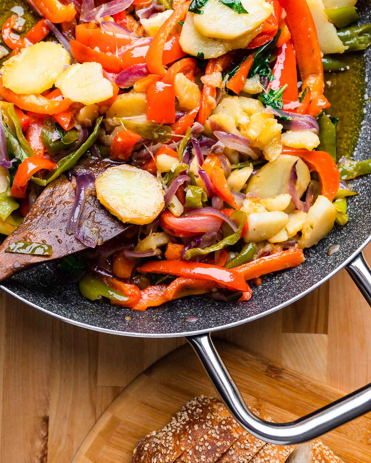 Large pan of peppers and potatoes with Italian bread on the side.