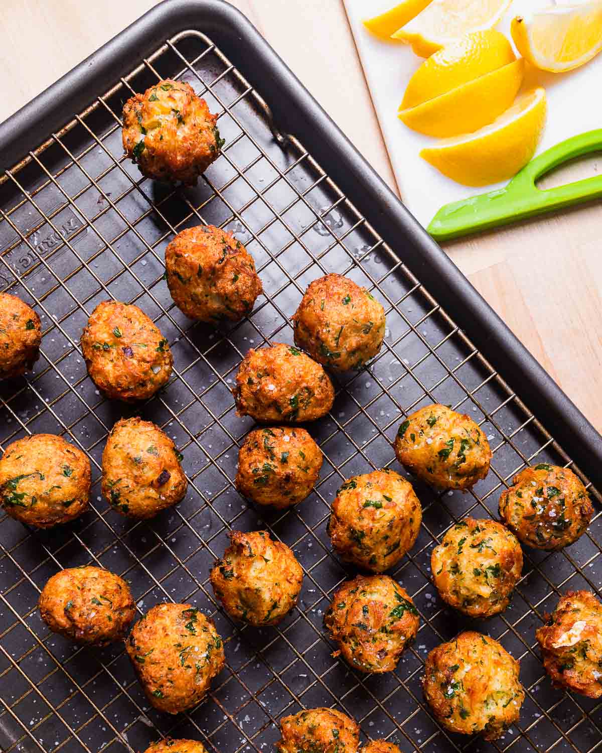 Baccala balls on wire rack and lemons wedges on the side.