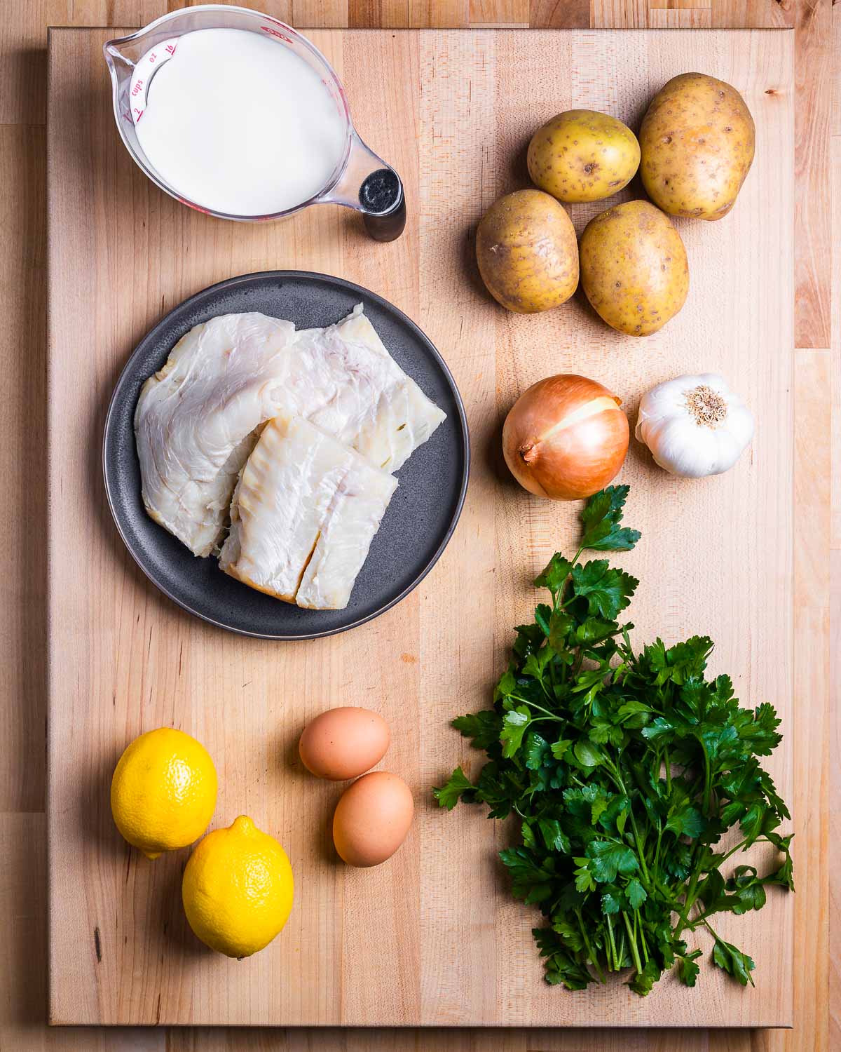 Ingredients shown: milk, potatoes, baccala (salt cod), onion, garlic, lemons, eggs, and parsley.