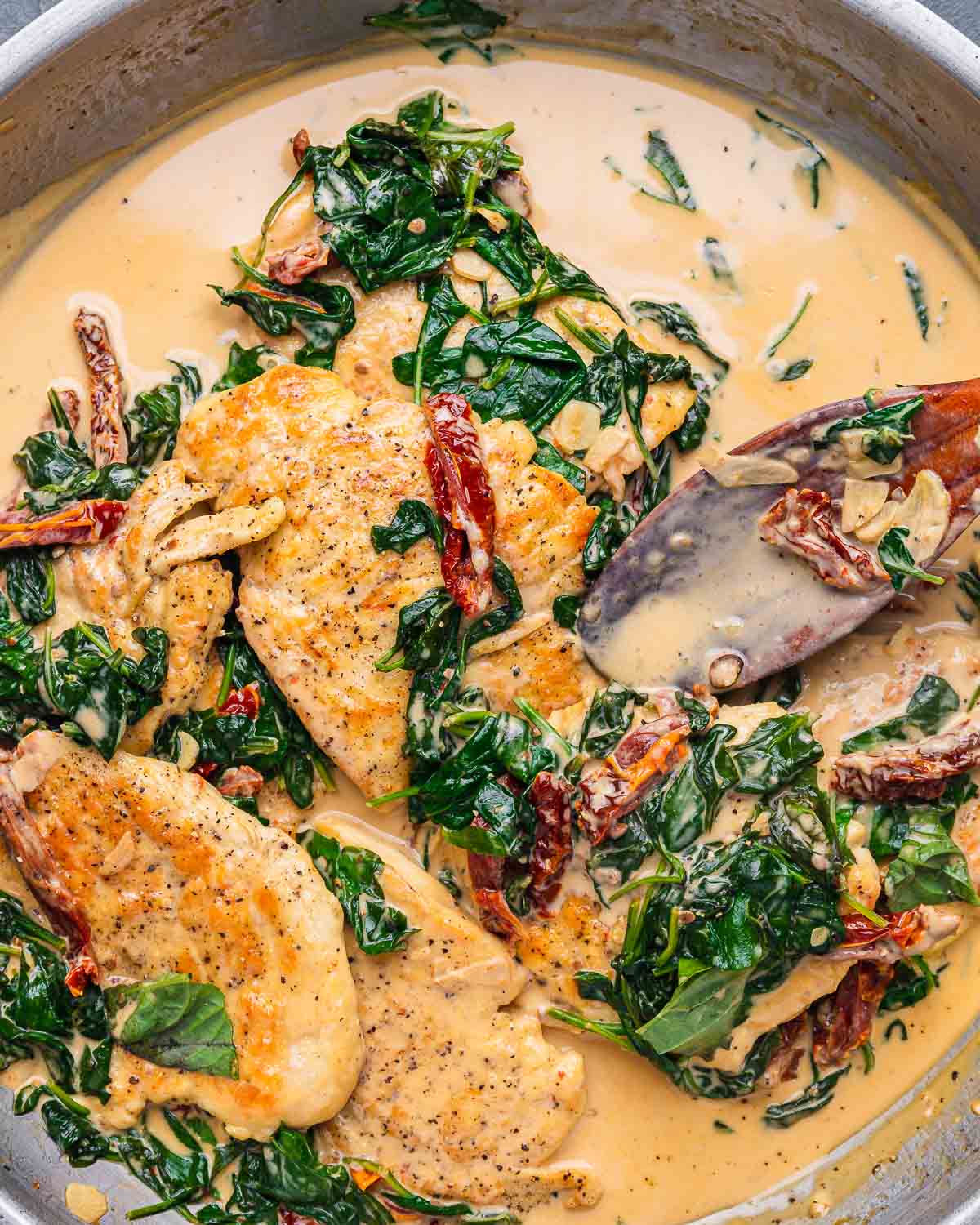 Sun dried tomato chicken with spinach in pan.