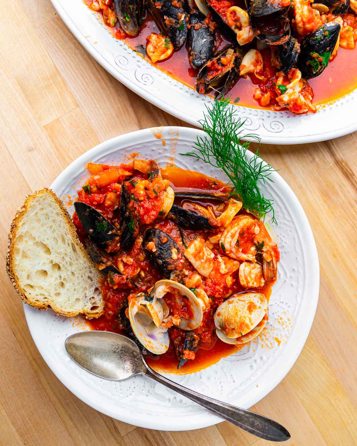 Overhead shot of white bowl with clams, mussels, and shrimp and toasted bread.