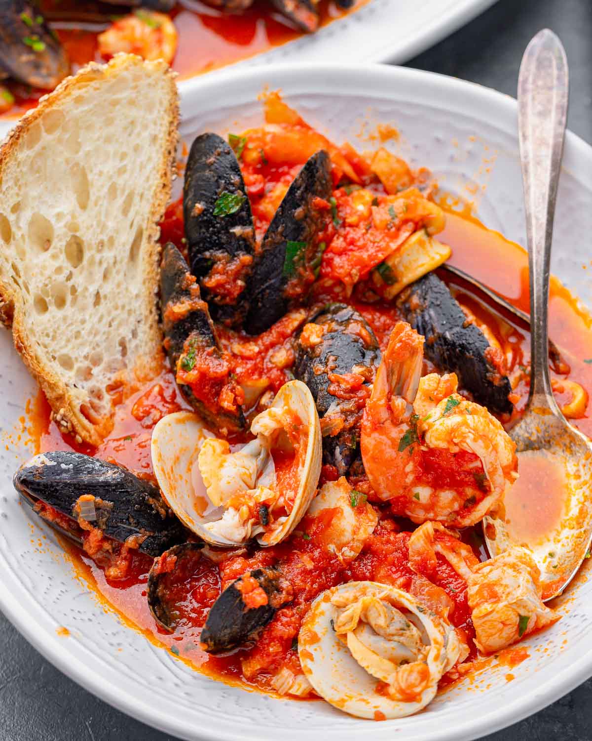 Zuppa di pesce in white bowl with toasted bread.