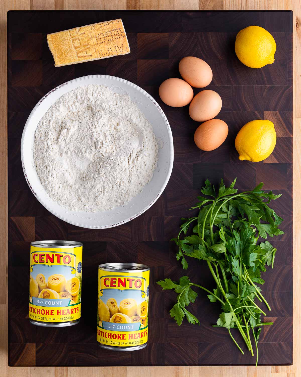 Ingredients shown: Parmigiano Reggiano, flour, eggs, lemons, canned artichoke hearts, and parsley.