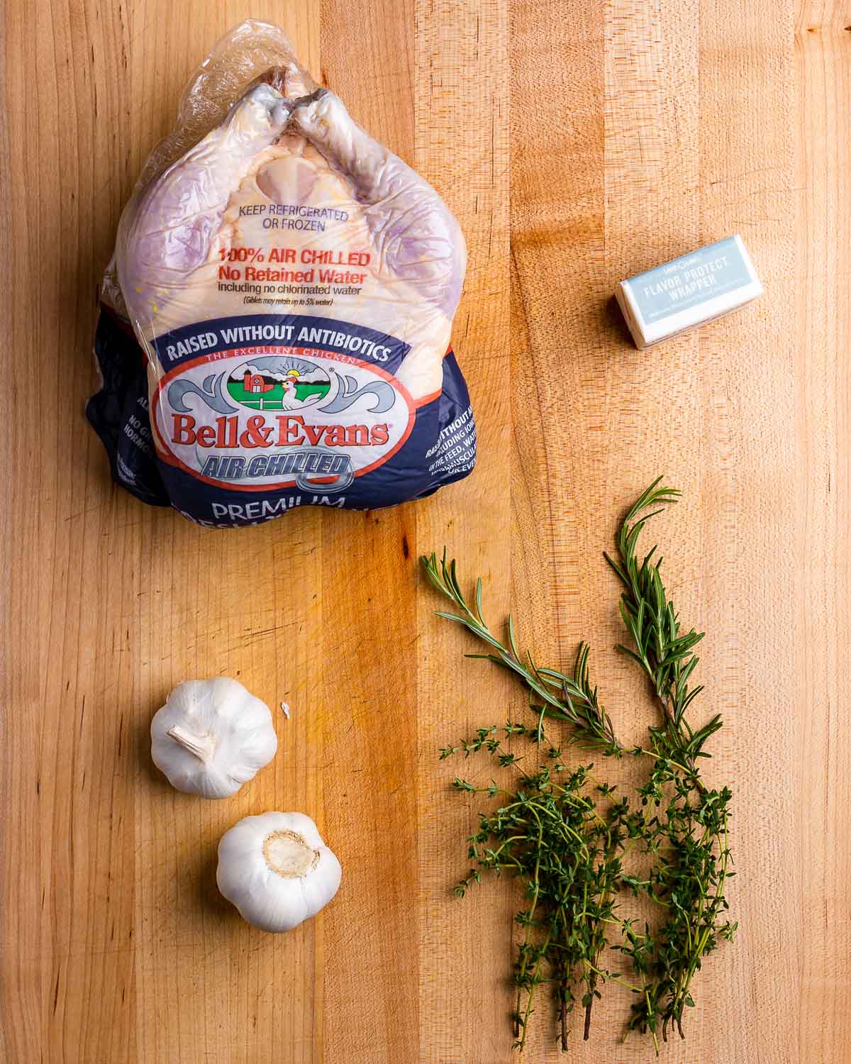 Ingredients shown: Whole chicken, butter, garlic, fresh rosemary and thyme.