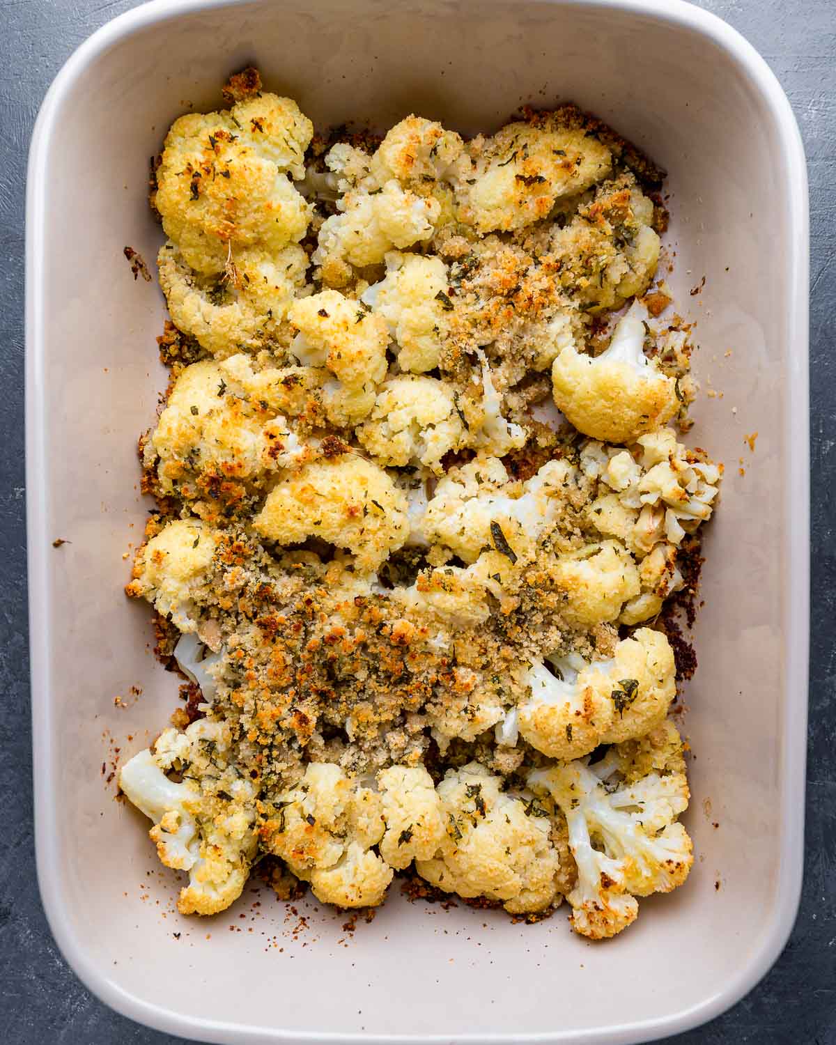 Baked cauliflower with cheese and breadcrumbs in large baking dish.