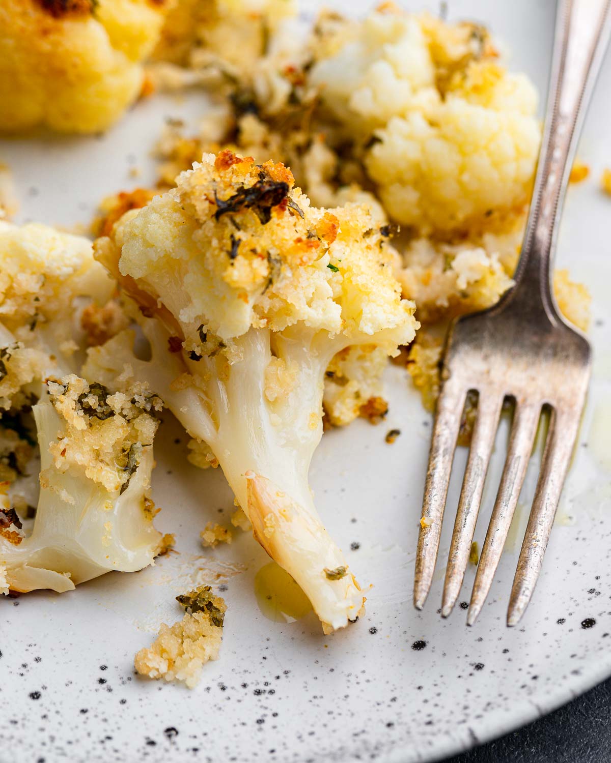 Roasted cauliflower with breadcrumbs and cheese in white plate.