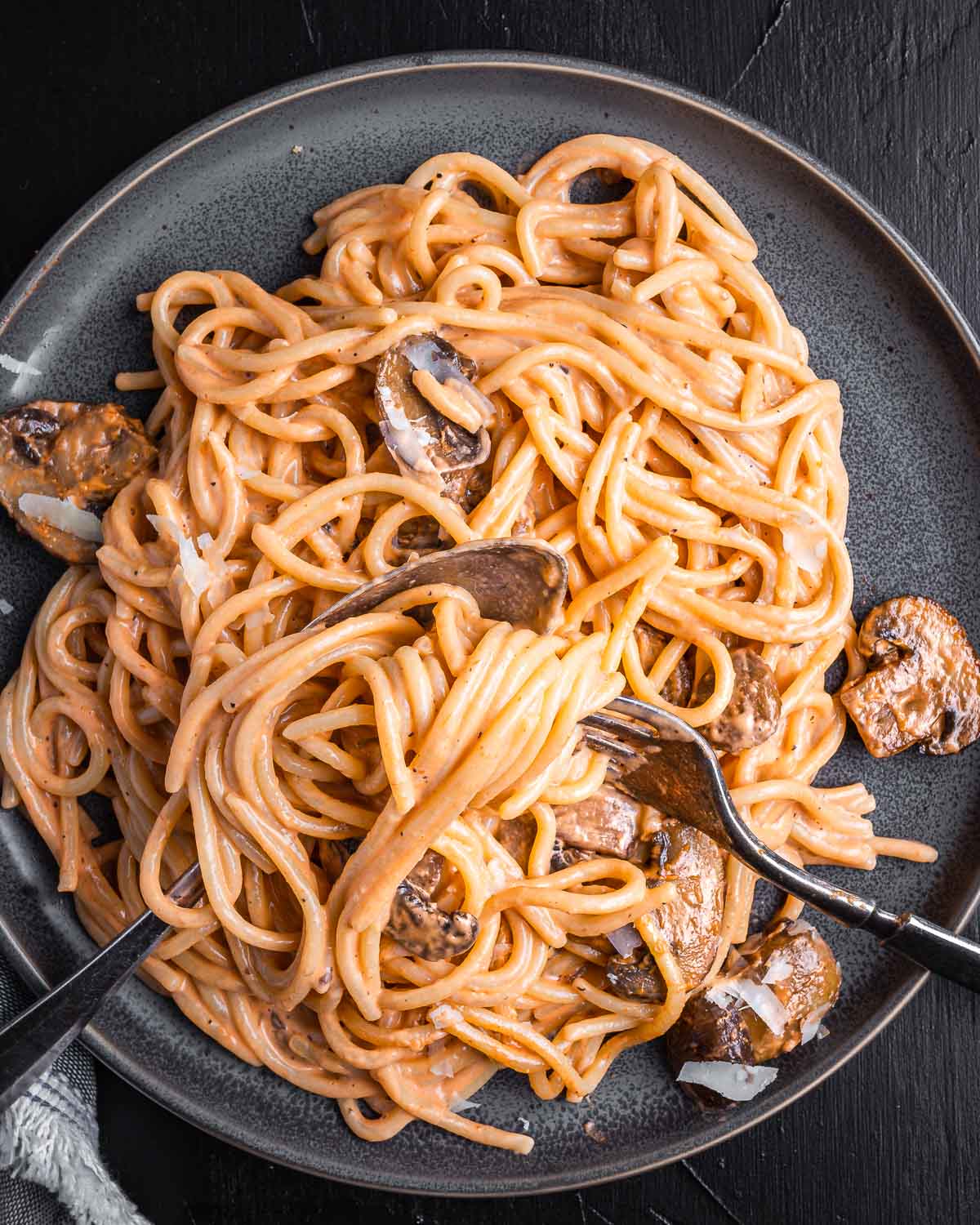 Mushroom brandy cream sauce spaghetti in grey plate on black board.