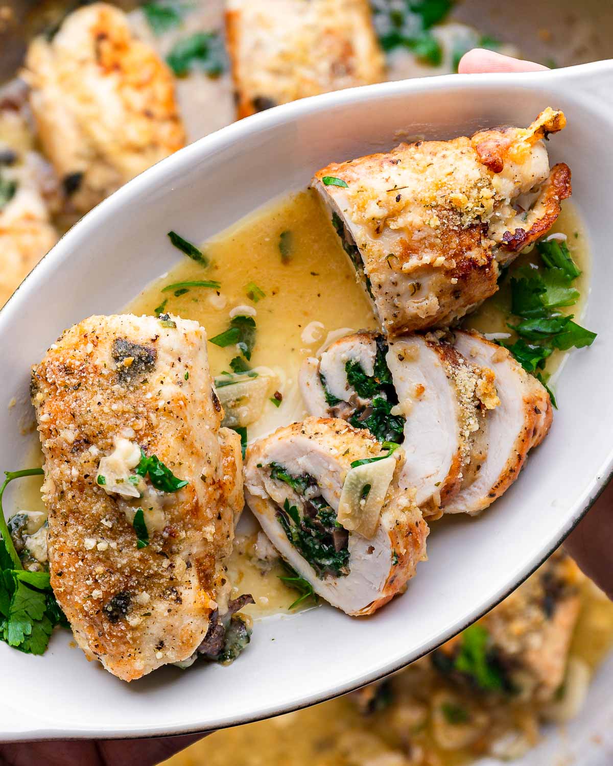 Hands holding small plate with sliced chicken involtini.