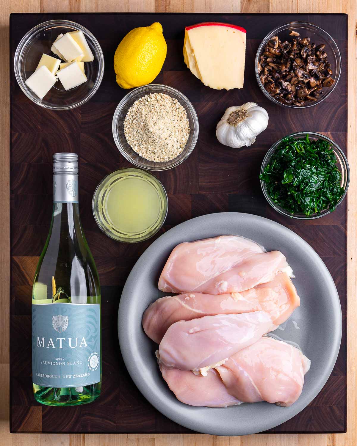 Ingredients shown: butter, lemon, breadcrumbs, cheese, garlic, spinach, mushrooms, chicken stock, white wine, and chicken breasts.