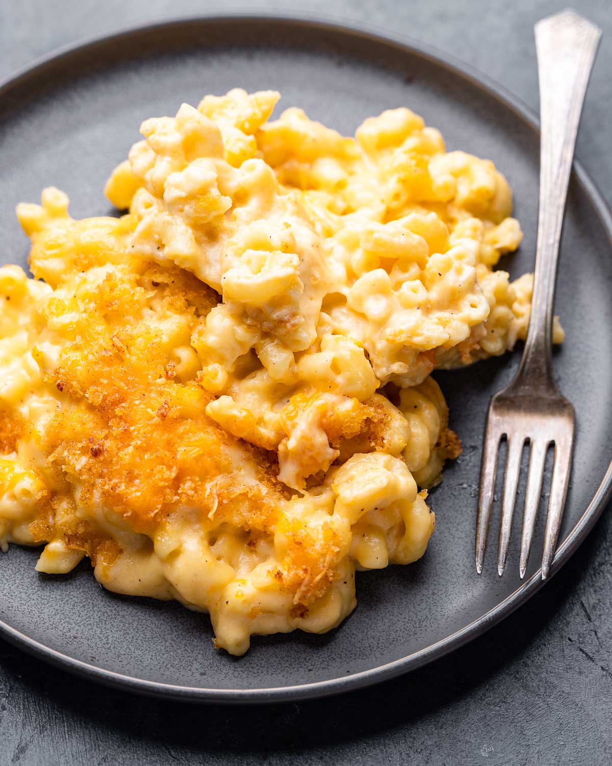 Baked macaroni and cheese in grey plate with fork.