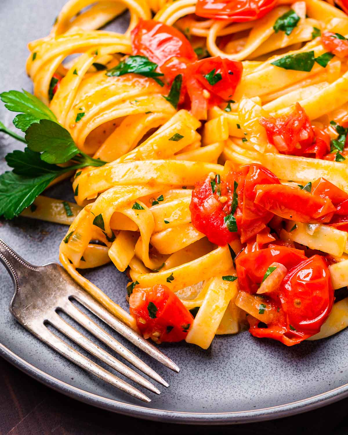 Fettuccine with cherry tomato butter sauce in grey plate.