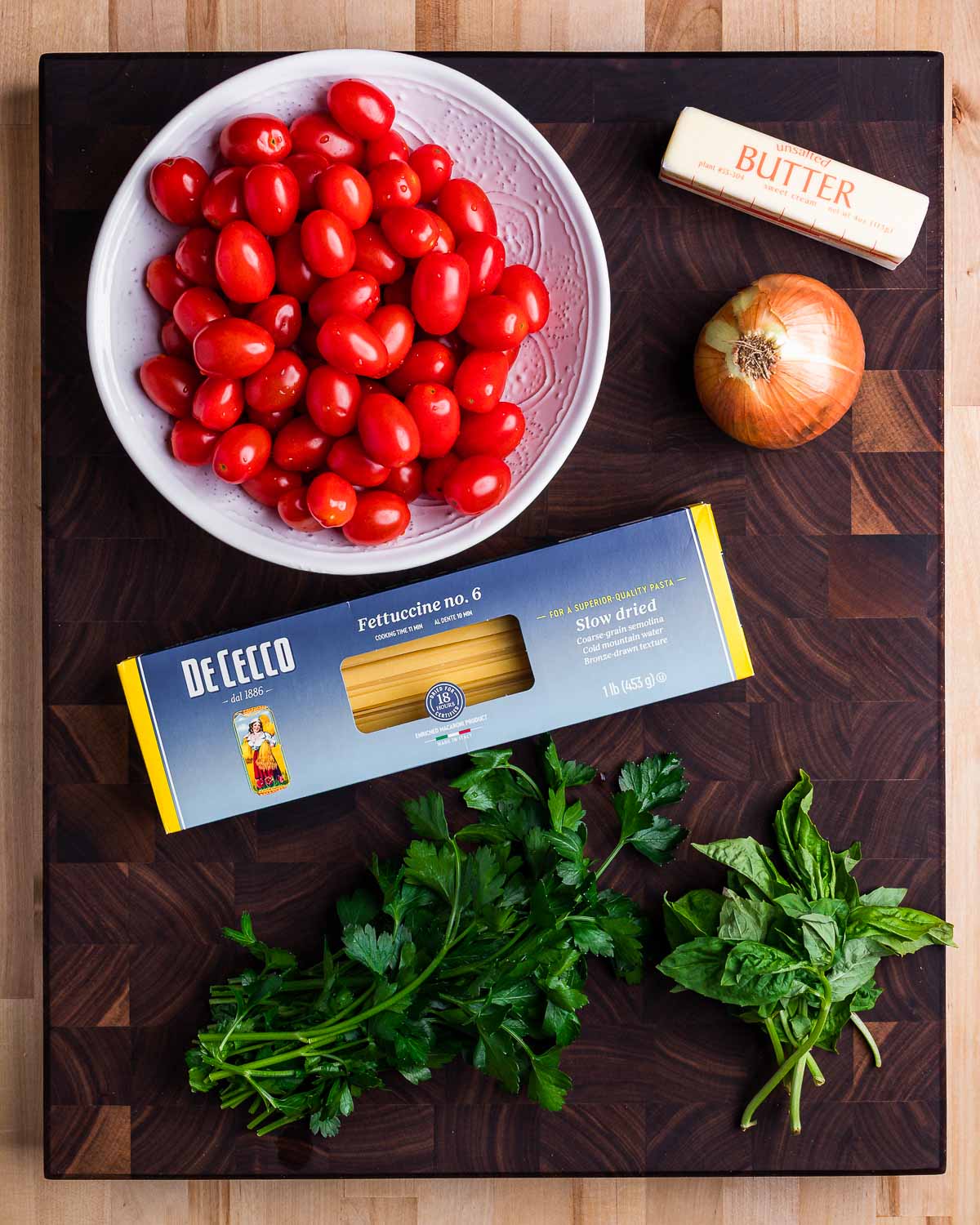 Ingredients shown: cherry tomatoes, butter, onion, fettuccine, parsley, and basil.