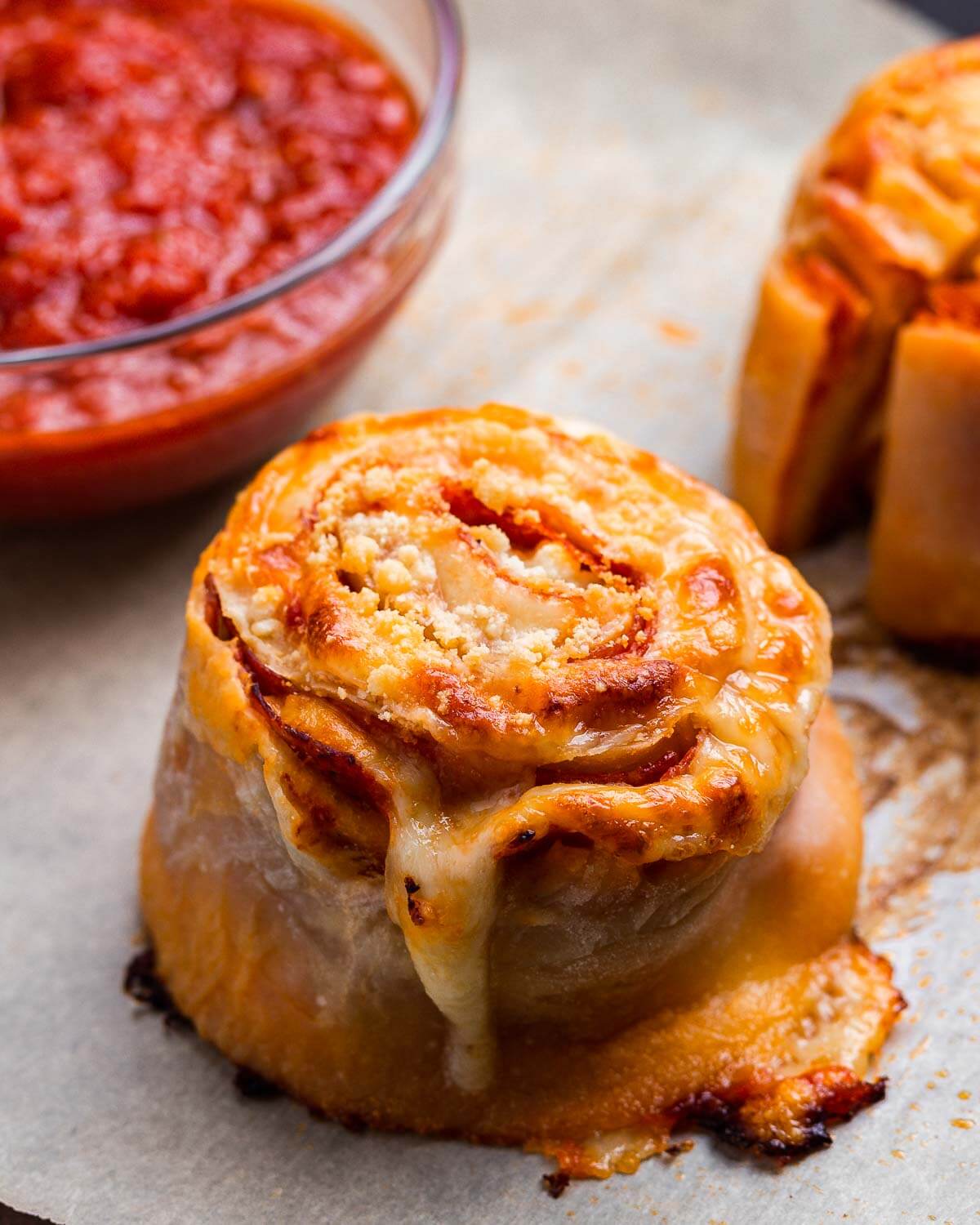 One pepperoni pinwheel with sauce bowl in background.
