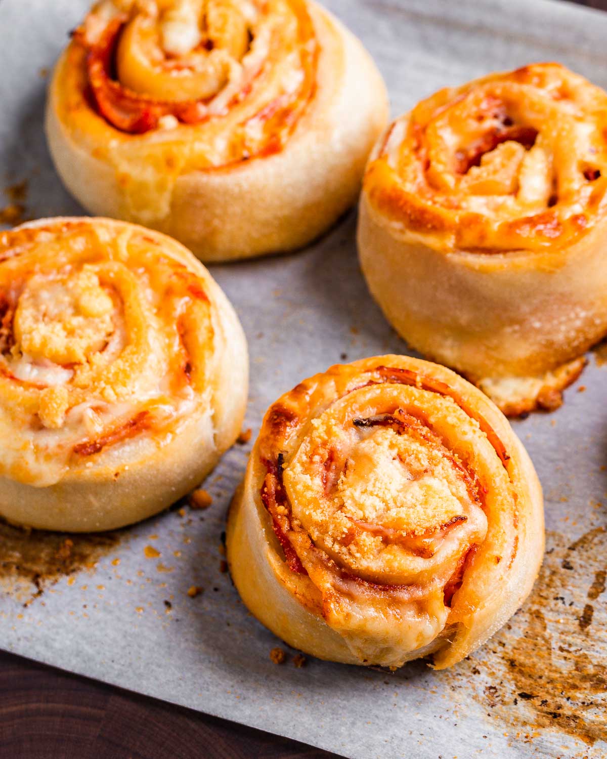 Cooked pepperoni pinwheels on parchment paper.