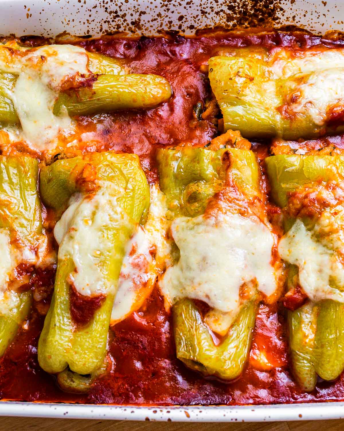 Cooked stuffed cubanelle peppers in baking dish.
