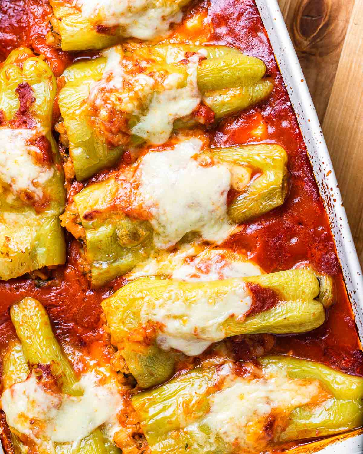 White baking dish with cooked stuffed cubanelle peppers.