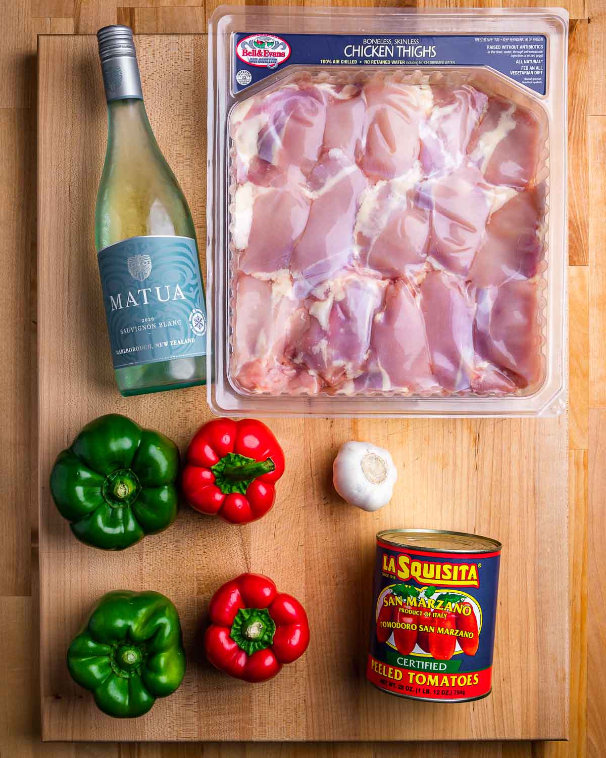 Ingredients shown: white wine, chicken thighs, bell peppers, garlic, and plum tomatoes.