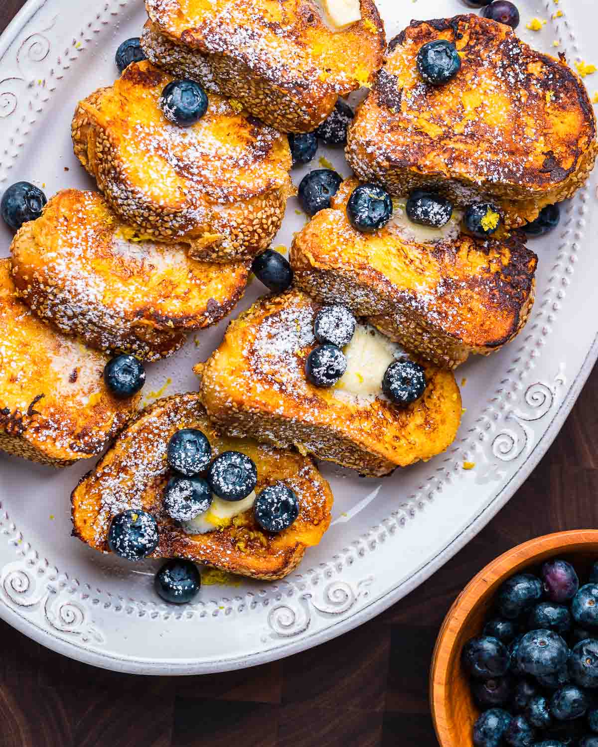 Platter of lemon blueberry French toast with bowl of blueberries on the side.