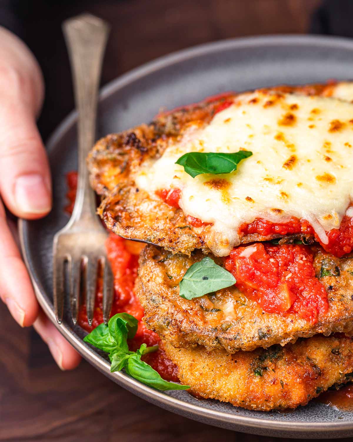 Close up shot of chicken eggplant parm held in hands.