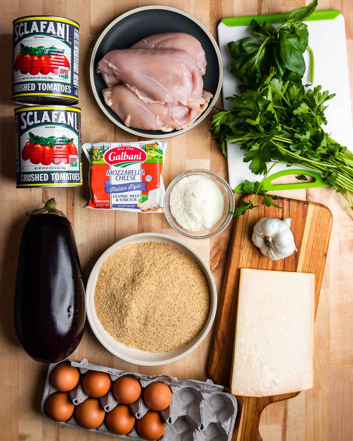 Ingredients shown: tomatoes, chicken, basil, parsley, cheeses, garlic, breadcrumbs, eggplant, and eggs.
