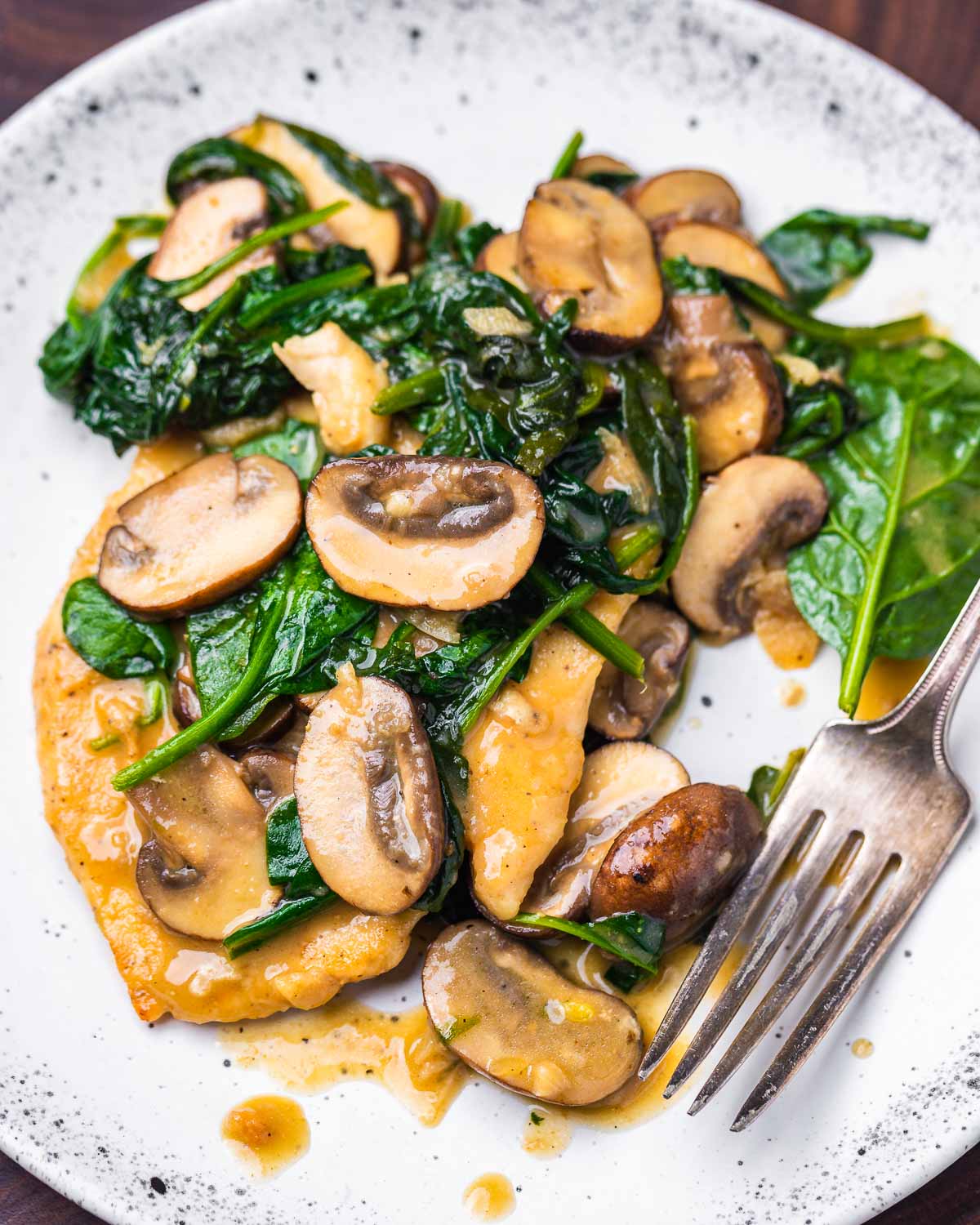 Spinach mushroom chicken in white plate.