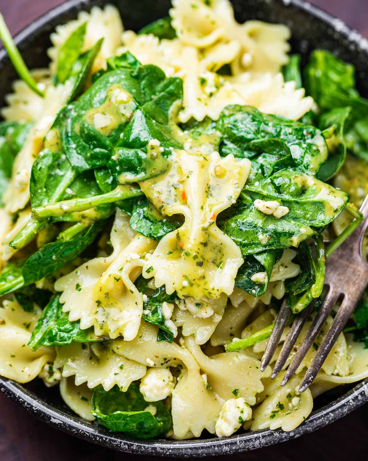 Spinach gorgonzola pasta salad in black bowl.