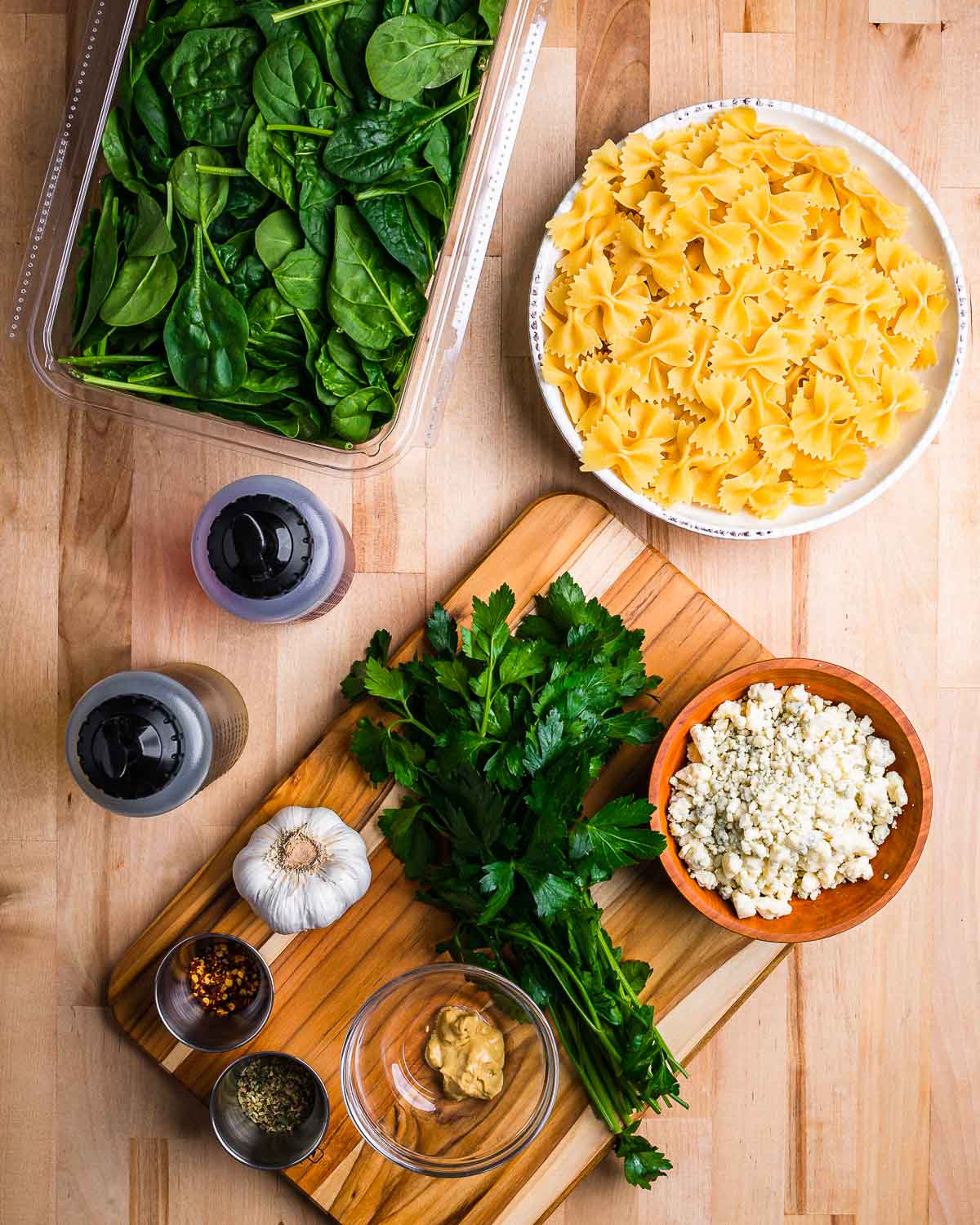 Ingredients shown: spinach, bow tie pasta, oil, vinegar, gorgonzola, parsley, garlic, mustard, red pepper flakes, and oregano.