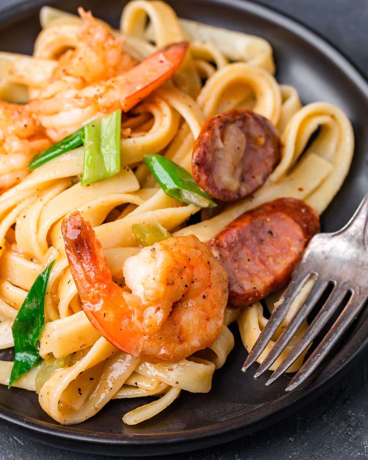 Cajun shrimp and sausage pasta in small plate with fork.