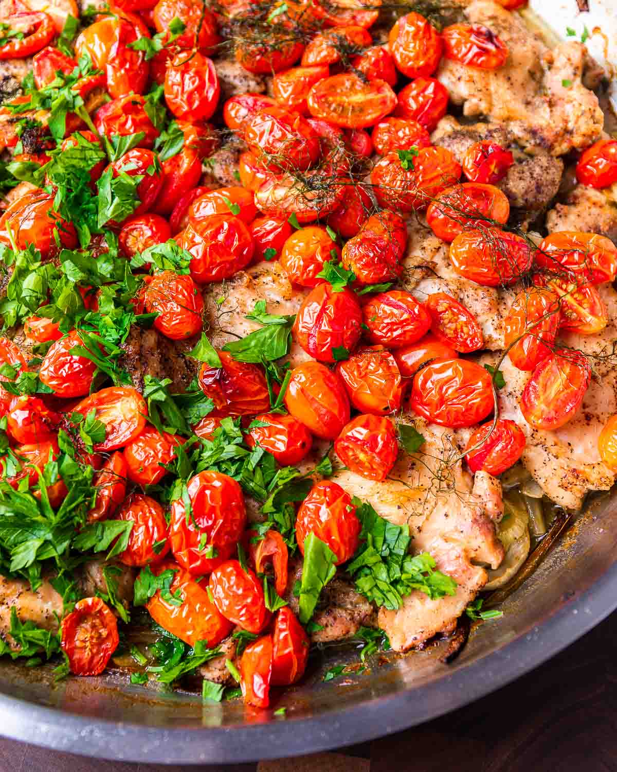 Chicken thighs with fennel and cherry tomatoes in large pan.