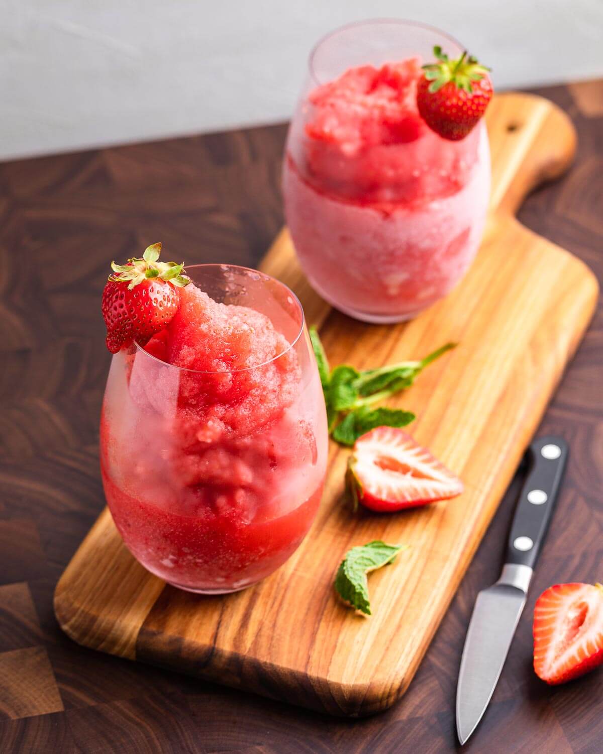 Two glasses of frosé on wooden cutting board.