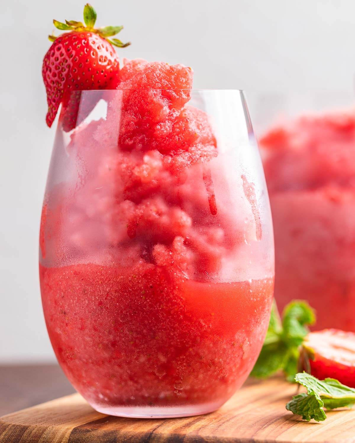 Closeup shot of frosé in glass with strawberry garnish.