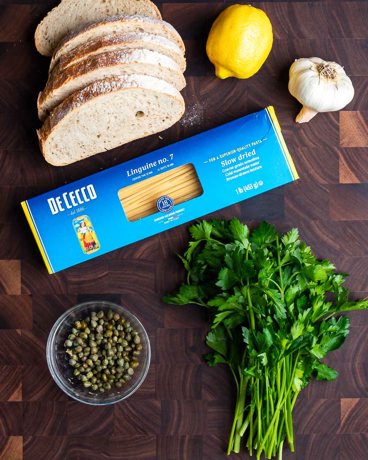 Ingredients shown: bread, lemon, garlic, linguine, capers, and parsley.