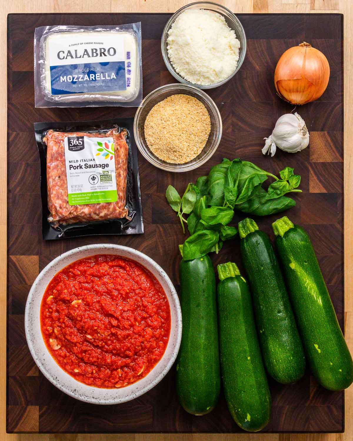 Ingredients shown: mozzarella, Pecorino, breadcrumbs, onion, garlic, bulk sausage, basil, zucchini, and marinara sauce.