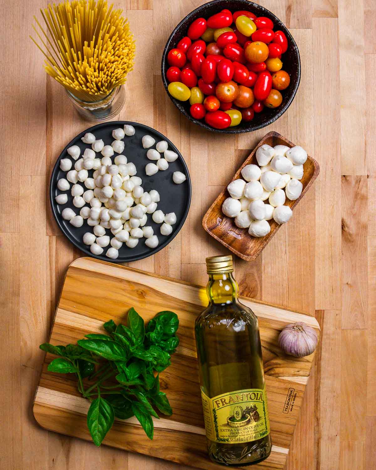 Ingredients shown: linguine, tomatoes, mozzarella balls, basil, olive oil, and garlic.