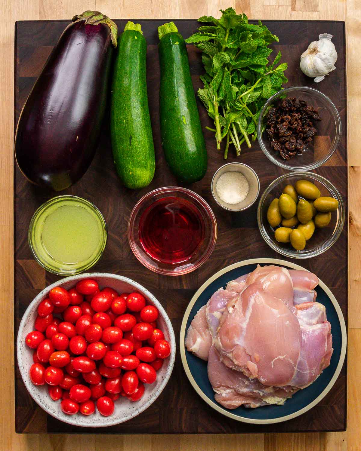 Ingredients shown: eggplant, zucchini, mint, garlic, raisins, sugar, chicken stock, vinegar, olives, tomatoes, and chicken thighs.