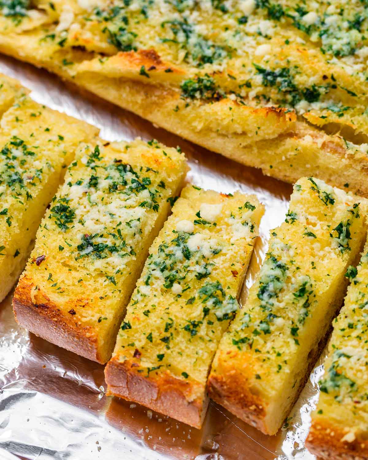 Pieces of garlic bread on foil baking sheet.